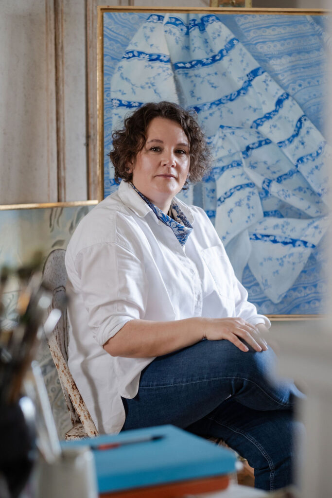 female artist sitting beside artwork